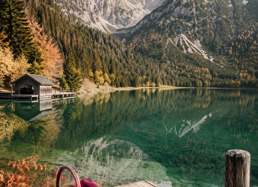 Kristallklarer Alpensee mit Picknickkorb und Holzsteg